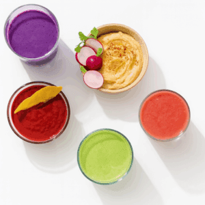 Overhead view of smoothies and dips in bowls and glasses on a white background