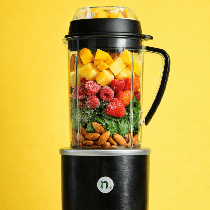 NutriBullet RX loaded with frozen fruit spinach and almonds before blending showing full capacity