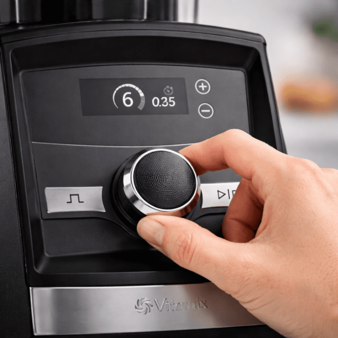 Hand adjusting Vitamix blender speed dial during blending process
