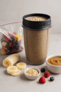 Frozen banana almond smoothie in a Nutri Ninja cup with smoothie pack ingredients nearby