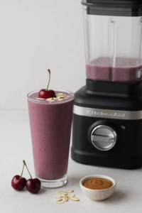 Cherry almond protein smoothie in tall glass beside KitchenAid K400